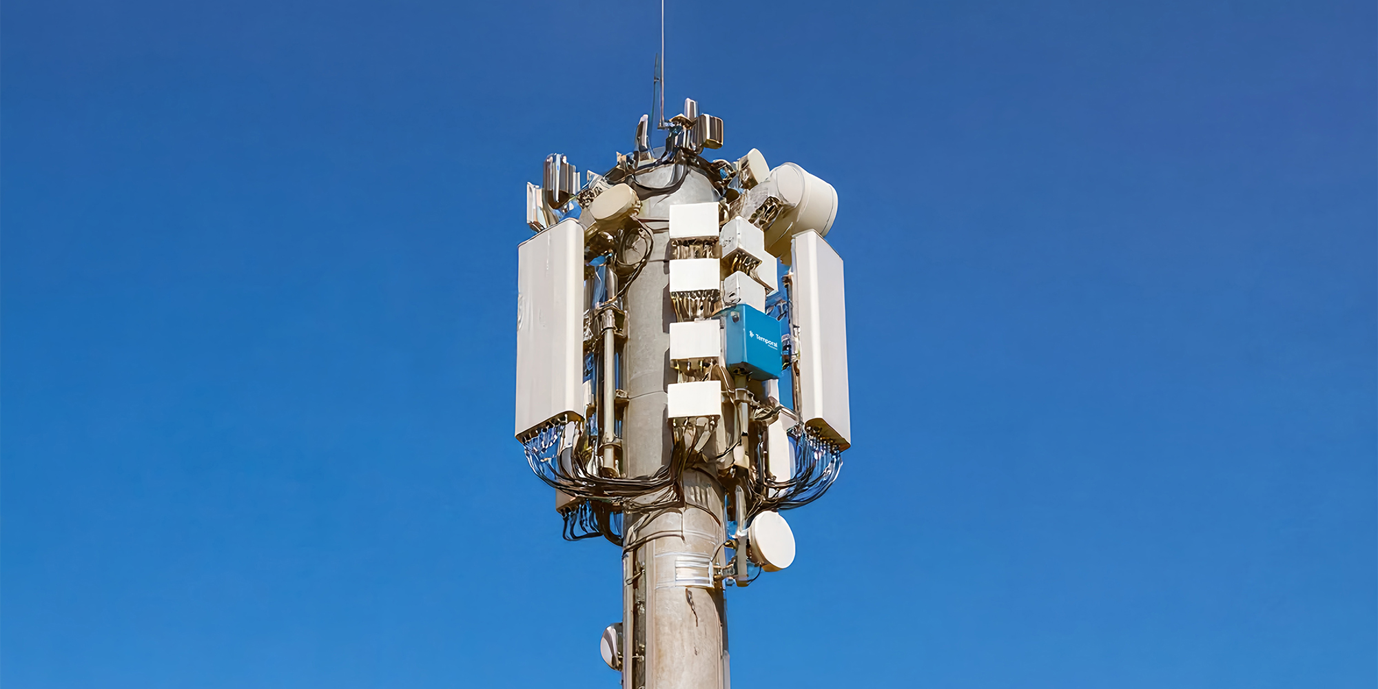 Telecom tower with multiple antennas and a blue box labeled Temporal against clear blue sky.